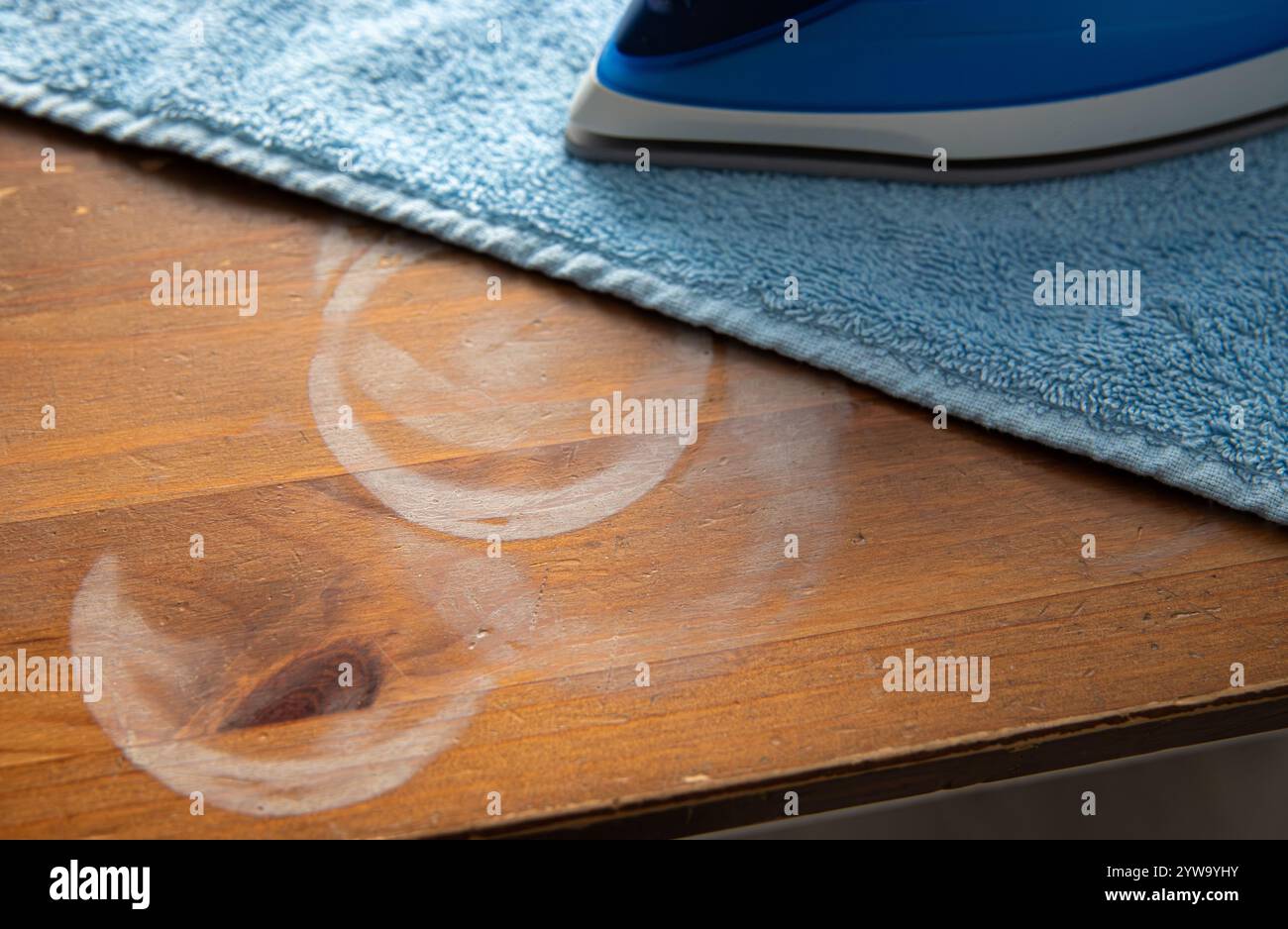 Concetto di rimozione delle macchie di calore rotonde bianche brutte dal tavolo della cucina di casa. Rimuovere le macchie di calore attraverso l'asciugamano con la macchina da stiro. Foto Stock