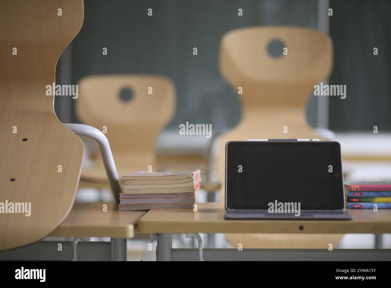 Mobili scolastici con un tablet nero e libri di testo in un'aula vuota. Baviera, Germania, Europa Foto Stock