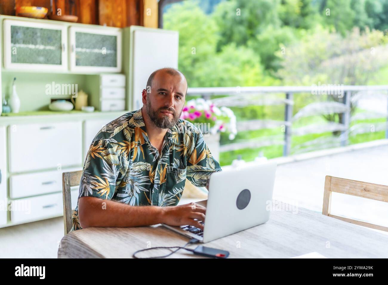 Nomade digitale che lavora su un laptop in uno chalet di montagna, godendo della libertà di lavorare in remoto e di uno stile di vita nomade Foto Stock