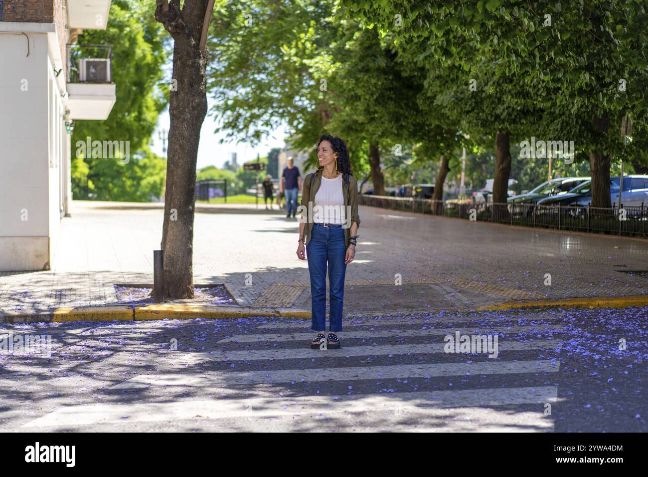 Donna sicura di sé in piedi su un passaggio pedonale in un vivace ambiente urbano Foto Stock