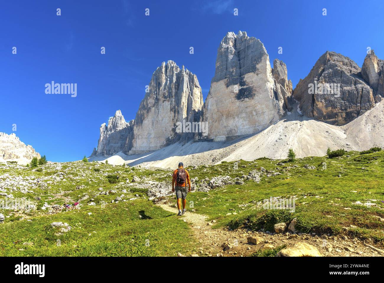 Turista che si gode un'escursione estiva su un sentiero panoramico che conduce alle maestose vette delle tre cime di lavaredo nelle dolomiti, in italia Foto Stock