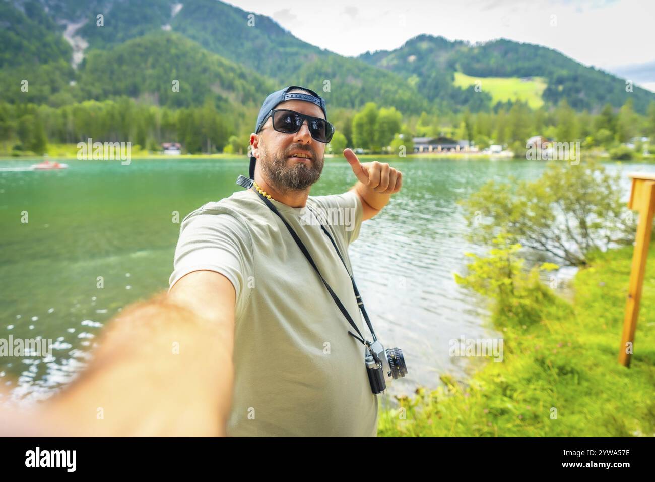 Turista che ama le vacanze estive sul lago di dobbiaco nelle dolomiti italiane, scattando un selfie e facendo gesti verso l'alto Foto Stock