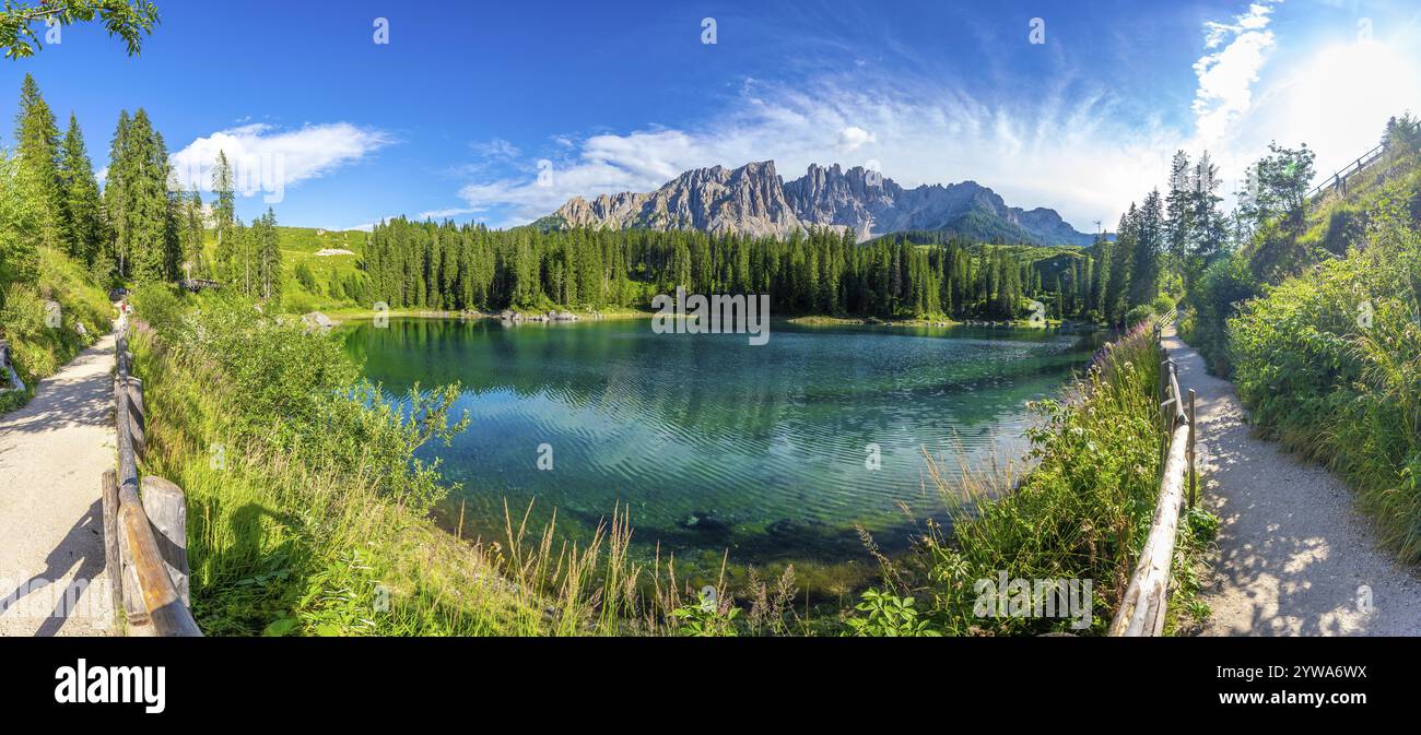 Le acque smeraldo riflettono la catena montuosa del latemar, creando uno scenario mozzafiato sul lago carezza, una popolare destinazione turistica nella dolomite italiana Foto Stock