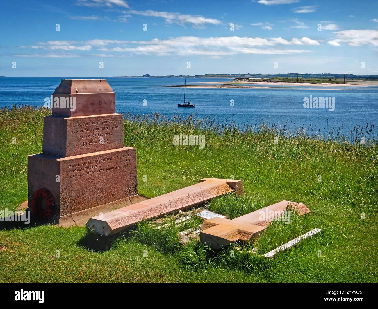 Regno Unito, Northumberland, Holy Island, Steel End, Holy Island War Memorial guardando verso il castello di Bamburgh. Foto Stock