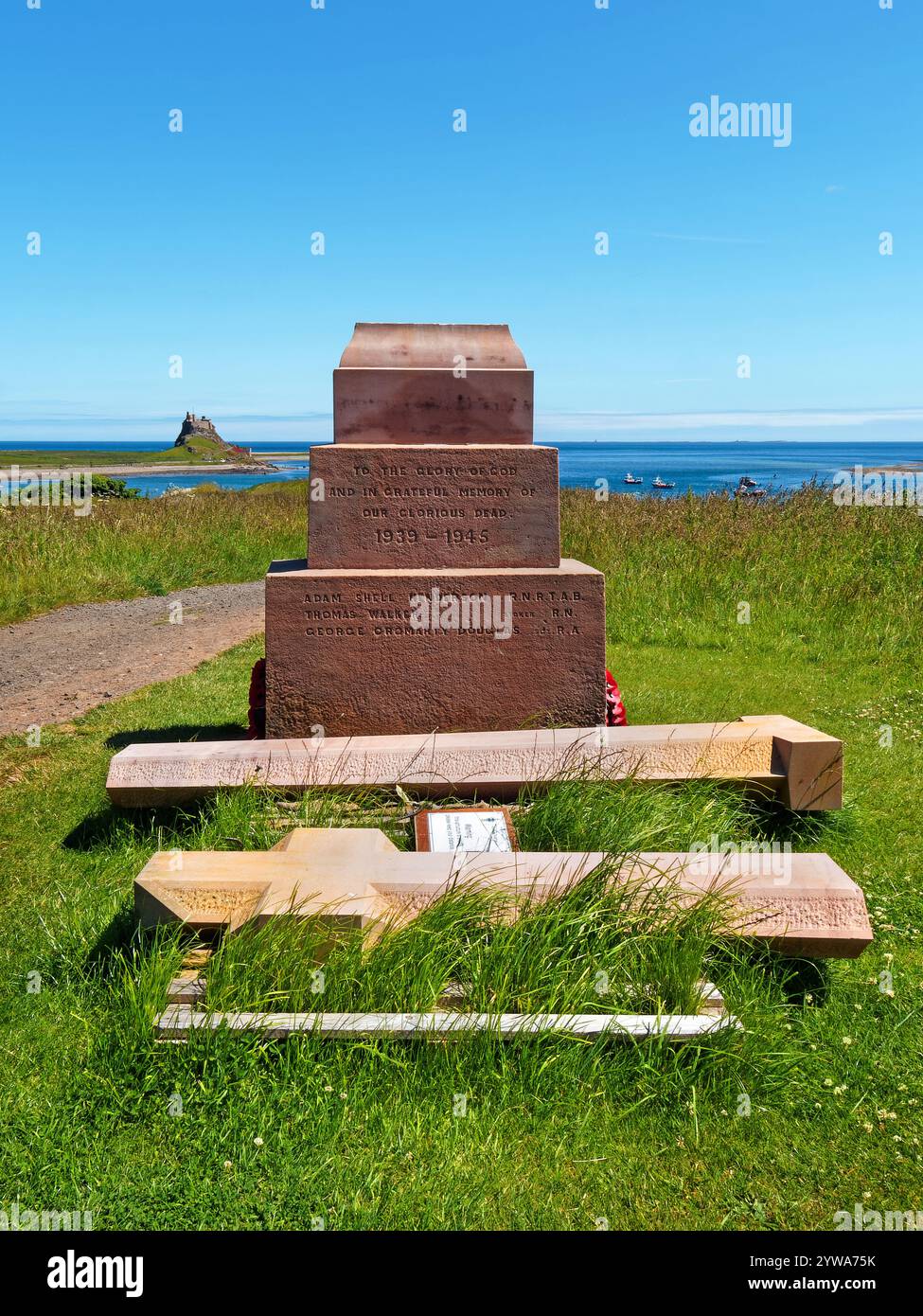 Regno Unito, Northumberland, Holy Island, Steel End, Holy Island War Memorial guardando verso il castello di Lindisfarne. Foto Stock
