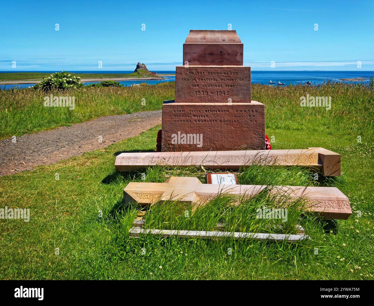 Regno Unito, Northumberland, Holy Island, Steel End, Holy Island War Memorial guardando verso il castello di Lindisfarne. Foto Stock