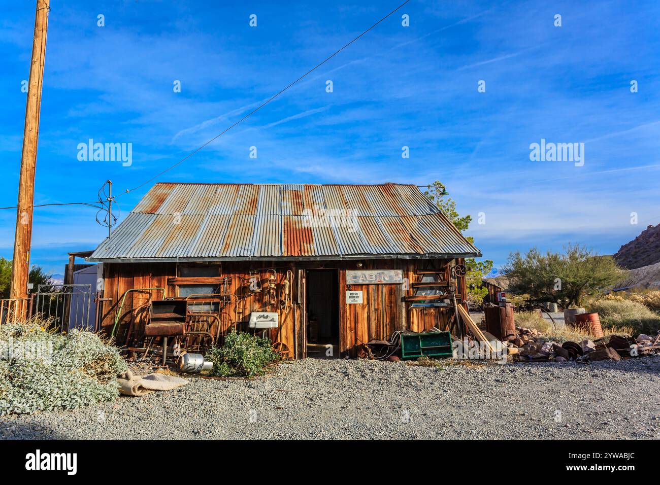 Una cabina rustica con un cartello sul davanti che dice "The Old Barn". La cabina è circondata da un vialetto di ghiaia e presenta alcuni oggetti in vecchio stile, come ad esempio Foto Stock