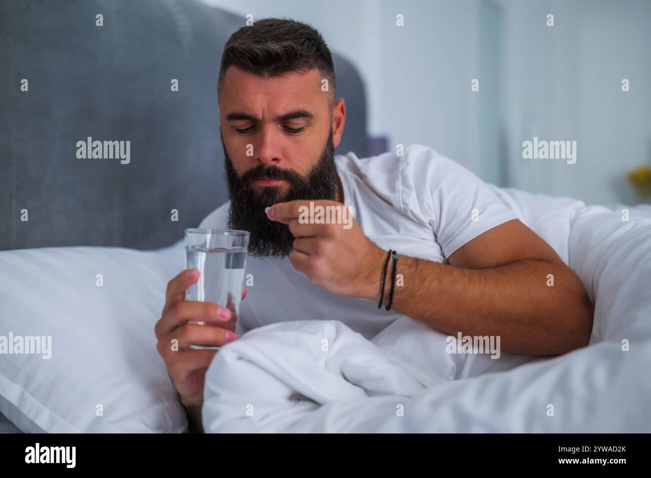 L'uomo non riesce a dormire. Sta prendendo pillole per dormire. Foto Stock