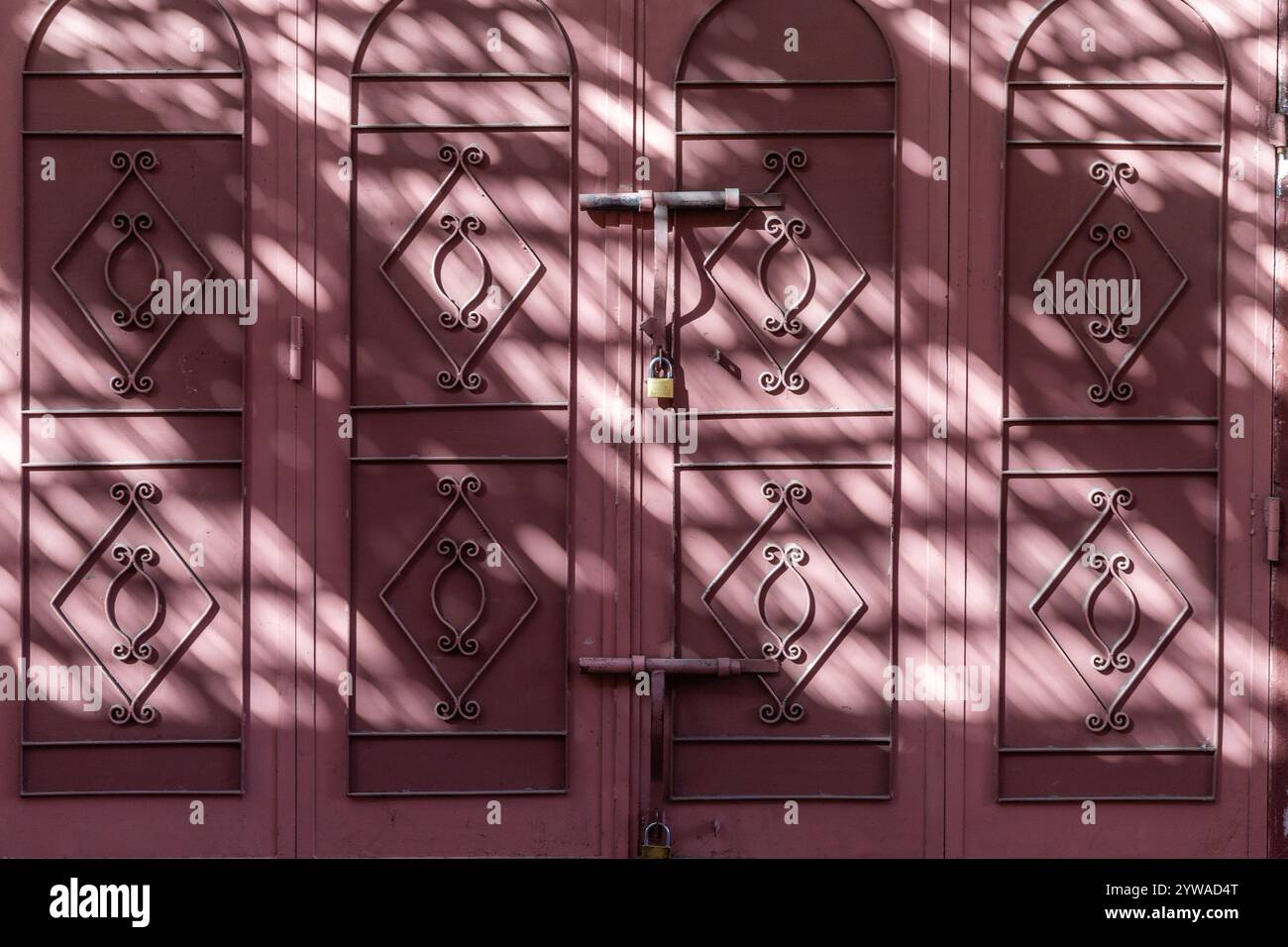Gioco d'ombra di protezione solare sulle porte metalliche chiuse di un negozio nella medina di Marrakech Foto Stock
