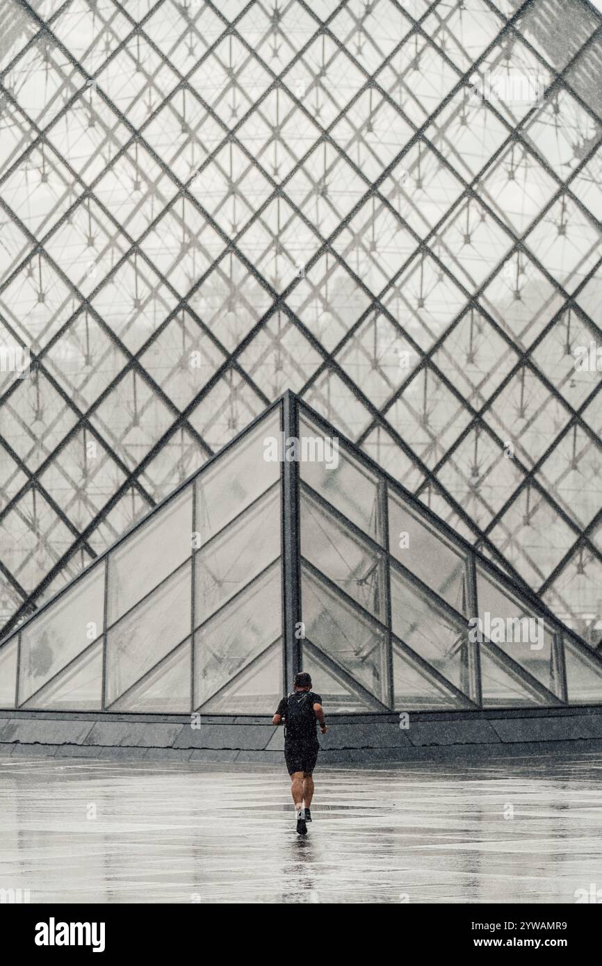 Armonia geometrica: Runner incontra la piramide del Louvre Foto Stock