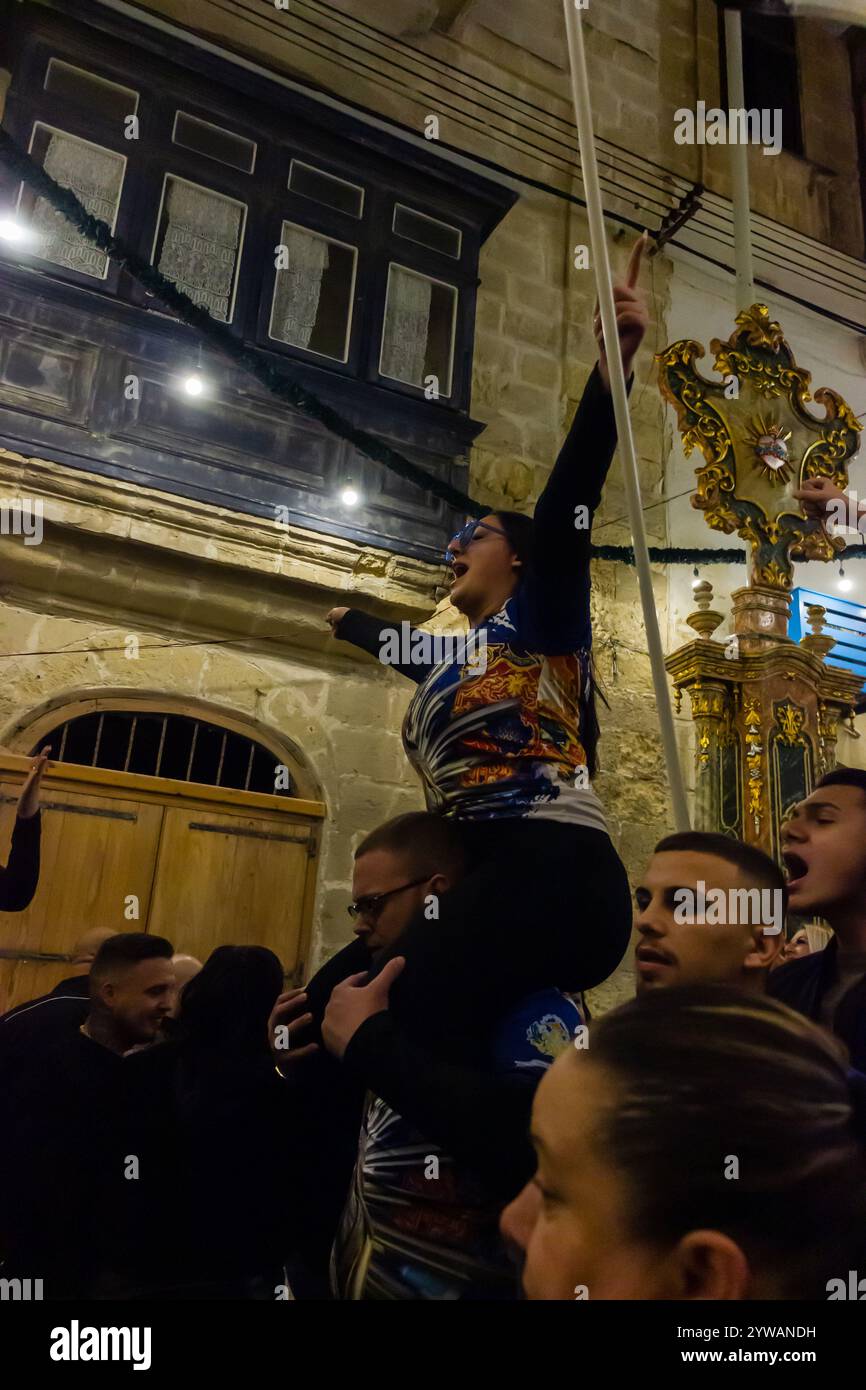 Cospicua, Malta - 6 dicembre 2024. Festa notturna eccitata con bandiere colorate e folla entusiasta Foto Stock