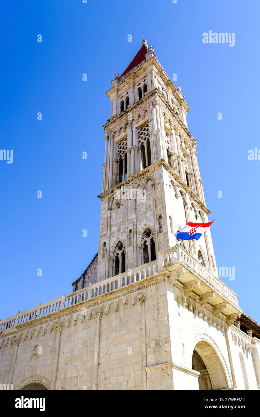 Campanile della cattedrale di San Lorenzo con bandiera croata a Traù, Croazia, sfondo blu del cielo Foto Stock