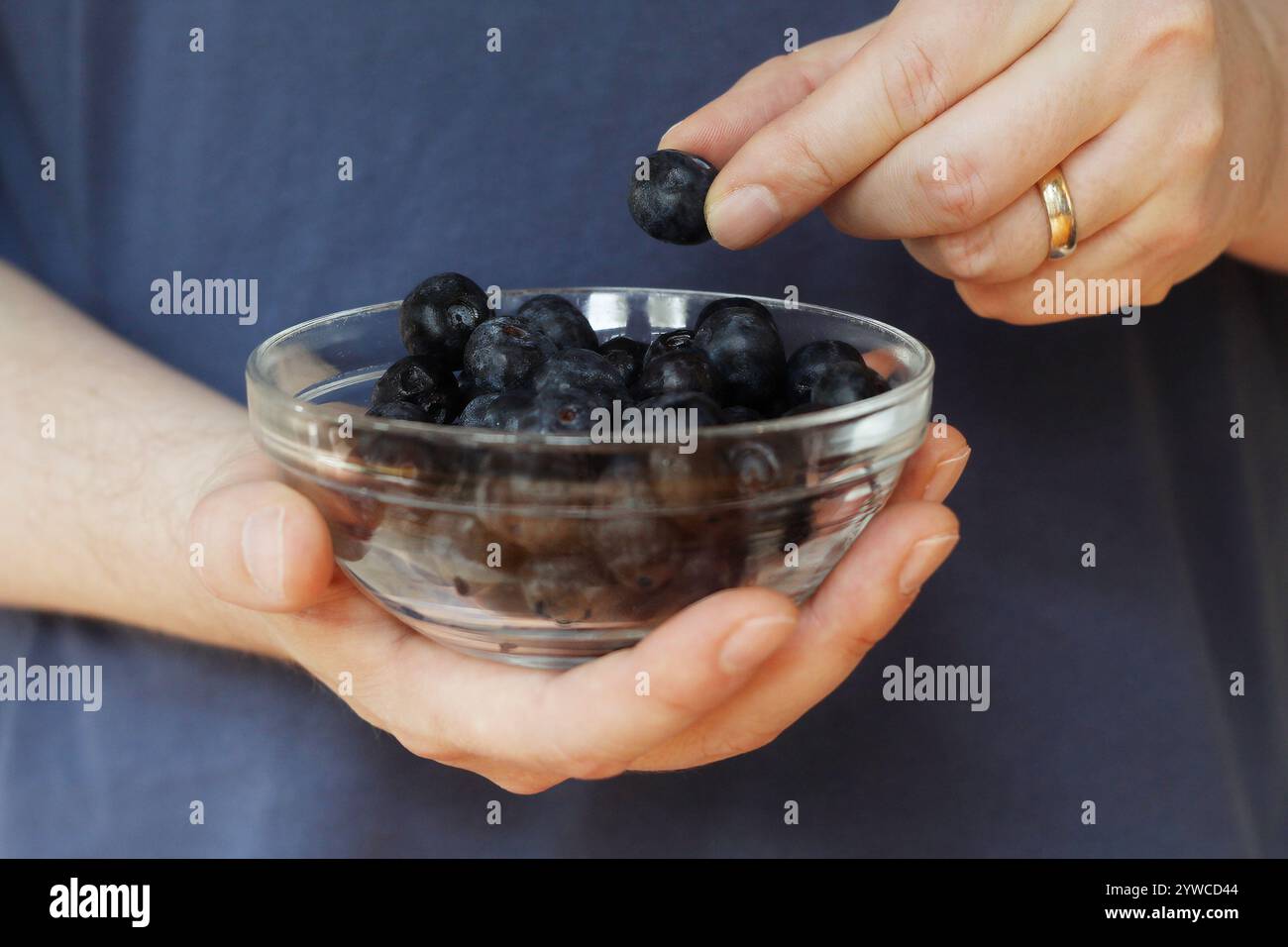 Primo piano di un maschio caucasico che tiene una ciotola di mirtilli. Foto Stock