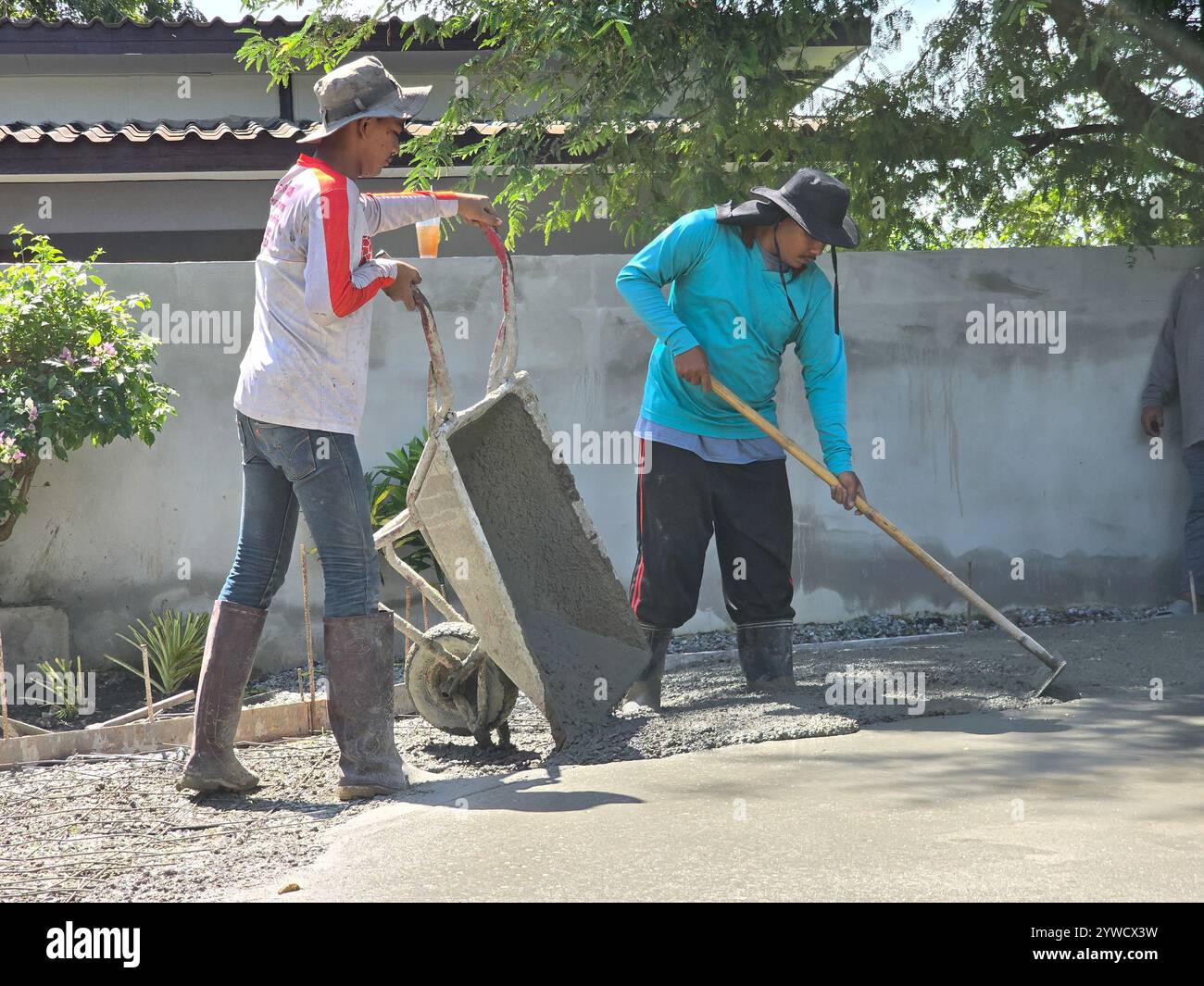 Pattaya, Thailandia 29 novembre 2024, due lavoratori collaborano diligentemente per creare una splendida superficie in cemento stampato in un'atmosfera vivace mentre posano il cemento con precisione. Foto Stock