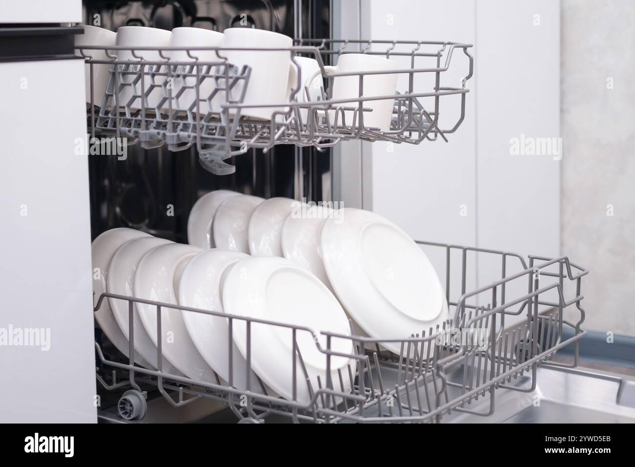 Sportello della lavastoviglie incorporato aperto. Cucina con elettrodomestici incorporati. Piatti e piatti sono lavabili in lavastoviglie. Foto Stock