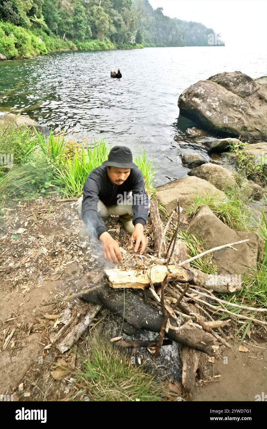 Un ranger che fa fuoco sul lato del lago di Gunung Tujuh in Gunung Tujuh, Kerinci, Jambi, Indonesia. Foto Stock
