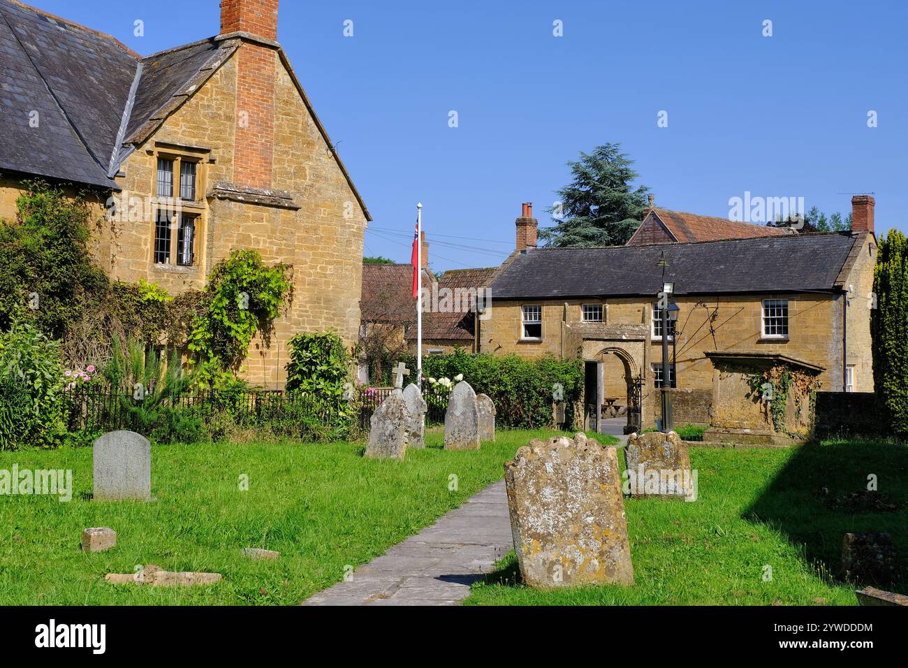 Martock: Cimitero e cancello di All Saints Church, The George, e edifici in pietra color miele a Martock, Somerset, Inghilterra, Regno Unito Foto Stock