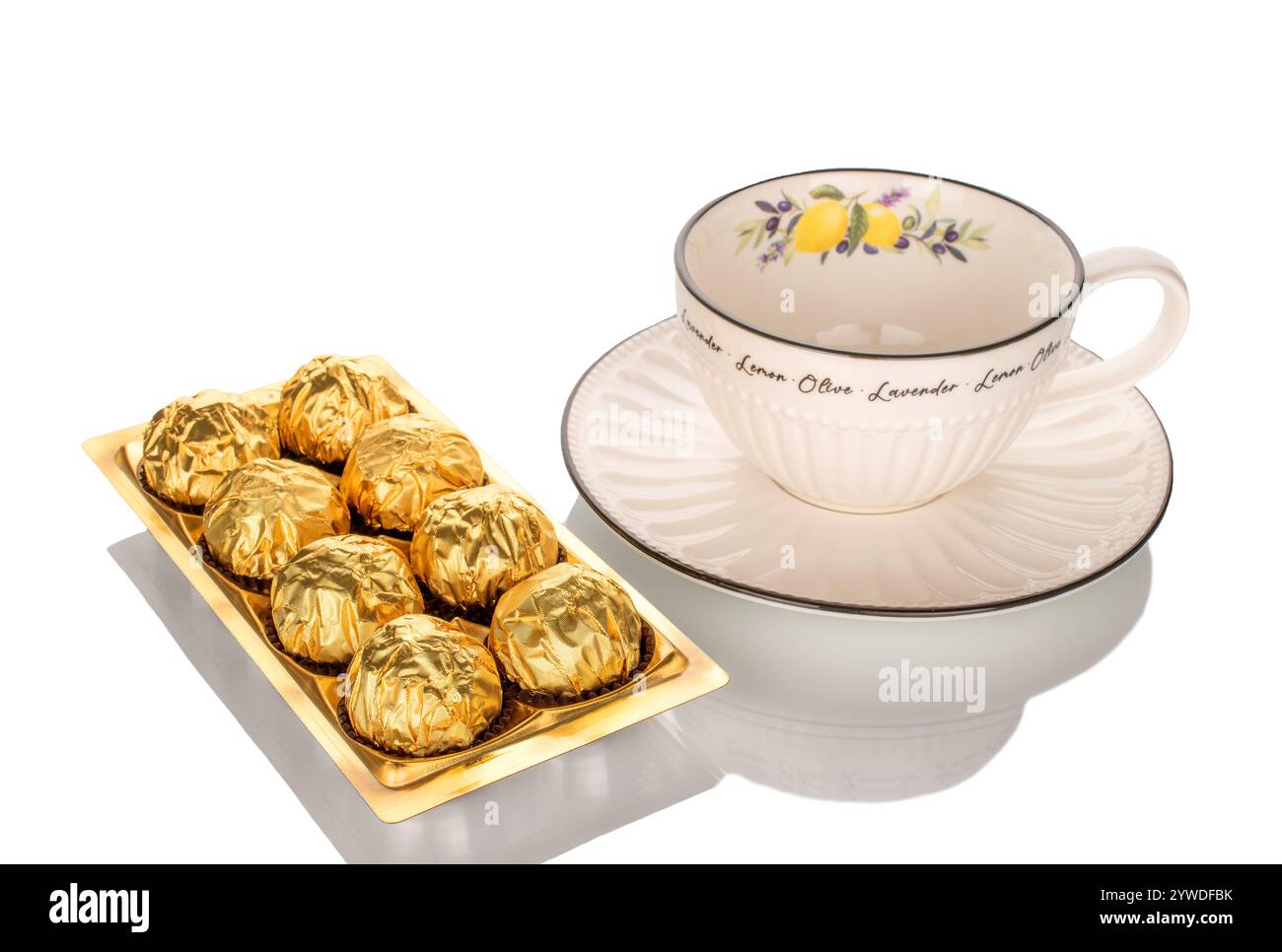 Diverse caramelle di cioccolato confezionate in carta regalo con piatti in ceramica, primo piano, isolate su sfondo bianco. Foto Stock