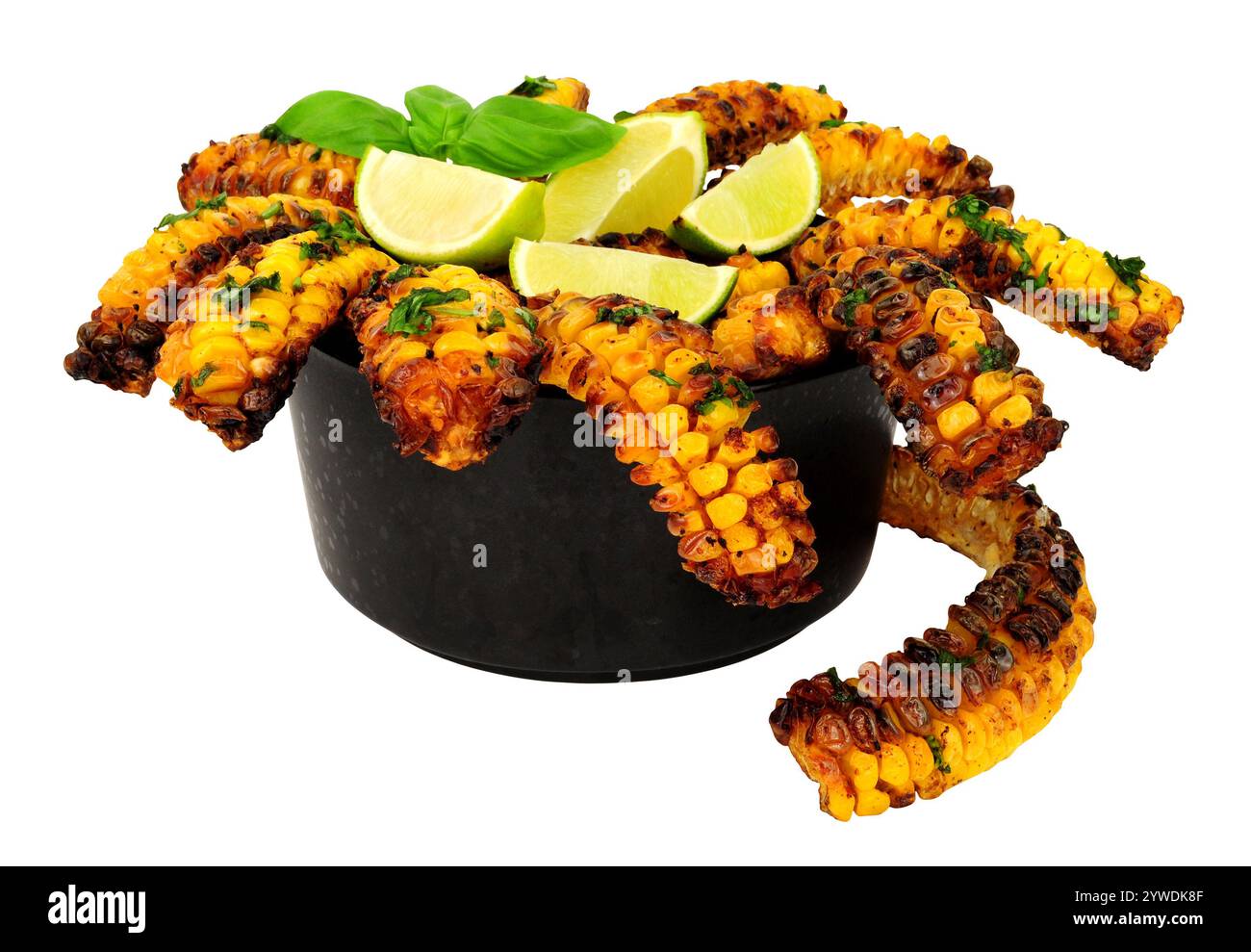 Porzione di costolette di mais dolce al forno con guarnizione alle erbe e spicchi di lime su una ciotola nera isolata su sfondo bianco Foto Stock