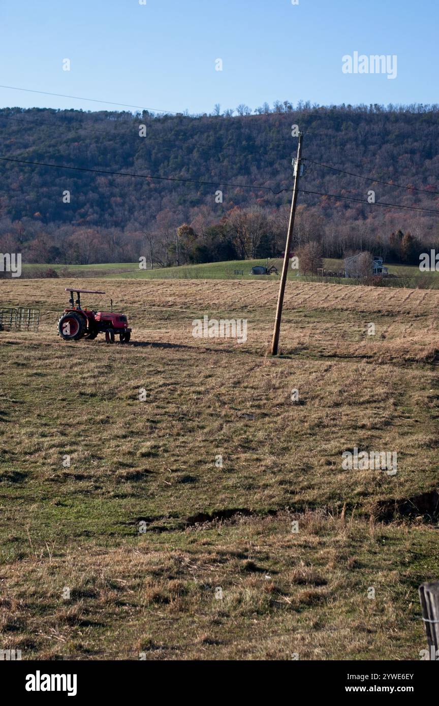 Trattore solitario in un campo vicino a un'asta di alimentazione Foto Stock