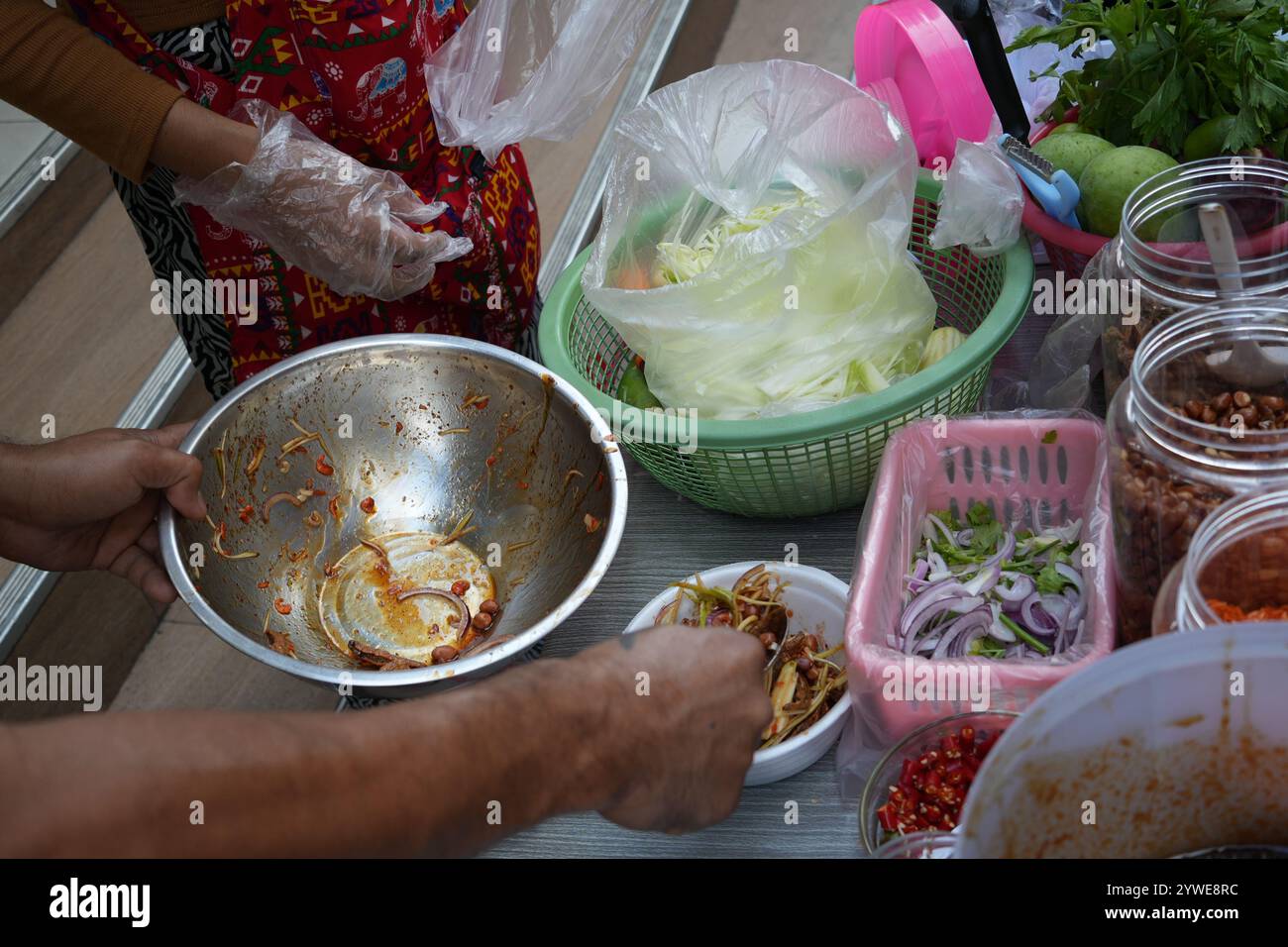 Cibo di strada a bangkok. Il fornitore di cibo prepara l'insalata Som Tam al mercato alimentare notturno. Mescolando mango o papaya e spezie, piccanti e aspri Foto Stock