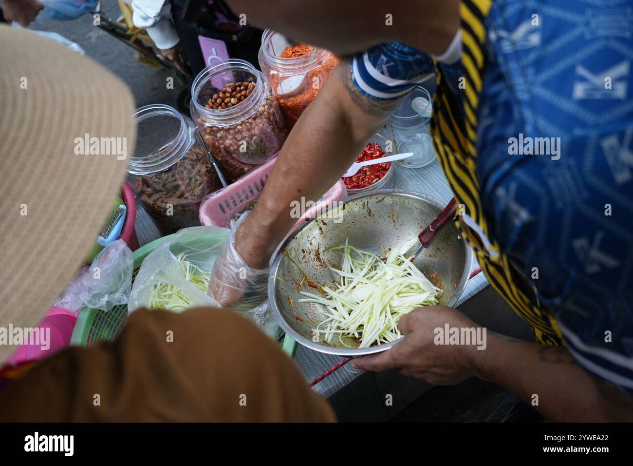 Cibo di strada a bangkok. Il fornitore di cibo prepara l'insalata Som Tam al mercato alimentare notturno. Mescolando mango o papaya e spezie, piccanti e aspri Foto Stock
