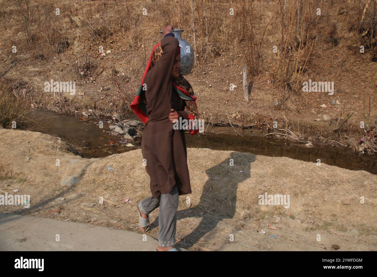 Srinagar, India. 10 dicembre 2024. Le donne di Sonabanjran, una remota zona collinare nel distretto di Pulwama del Kashmir meridionale, stanno affrontando gravi difficoltà a causa delle temperature gelide. Con l'alimentazione dell'acqua di rubinetto interrotta dal congelamento delle linee di alimentazione, i residenti sono stati costretti a raccogliere l'acqua potabile da un flusso congelato. (Foto di Nisar UL Haq Allaie/Pacific Press) credito: Pacific Press Media Production Corp./Alamy Live News Foto Stock