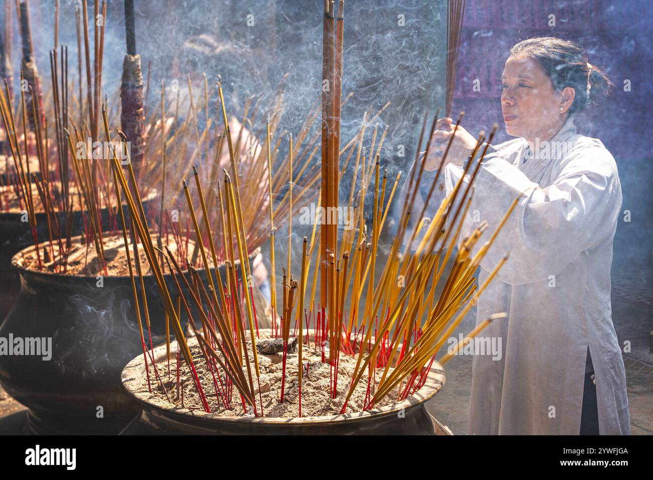 Donna che brucia incensi nel tempio cinese noto come Pagoda di Thien Hau a ho chi Minh, Vietnam Foto Stock