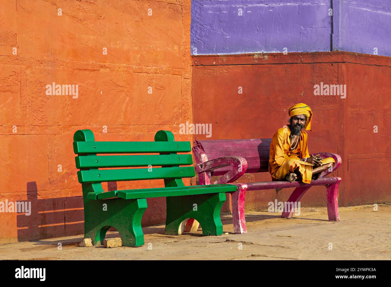 Uomo locale sulla panchina con pareti colorate a Varanasi, India Foto Stock
