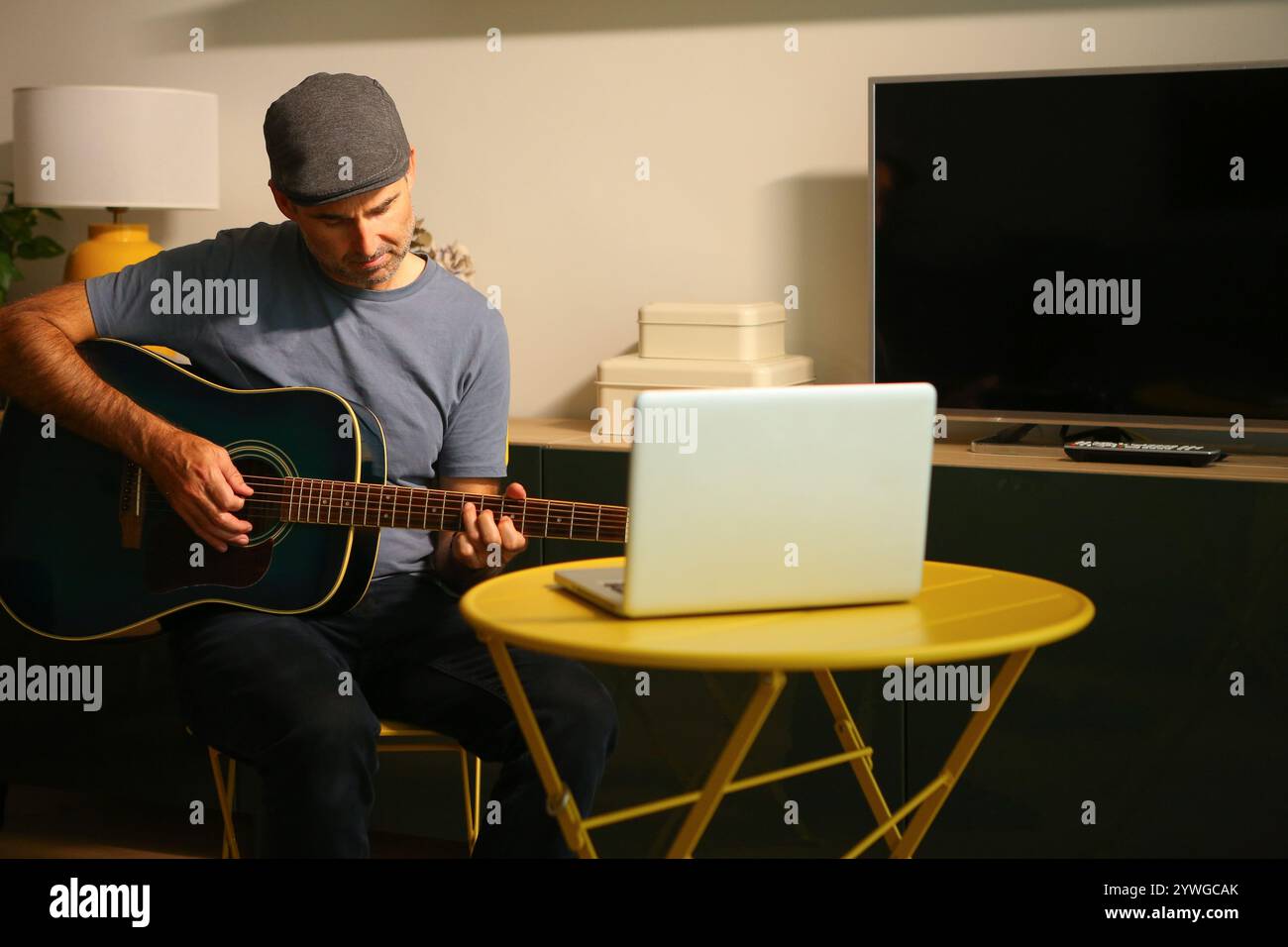 Un uomo seduto di fronte al computer che pratica lezioni di musica online Foto Stock