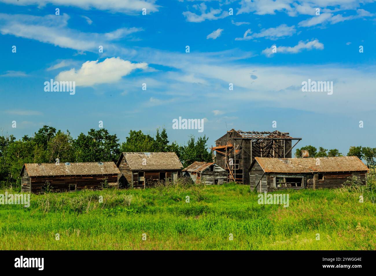 Una scena rurale con alcuni vecchi edifici e un grande campo vuoto. La scena è tranquilla e tranquilla Foto Stock