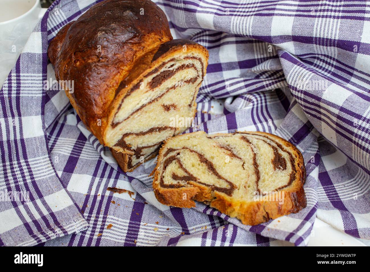 Cozonac, tradizionale pane dolce rumeno con ripieno di noci, tagliato a fette, su un panno a scacchi, vista laterale Foto Stock