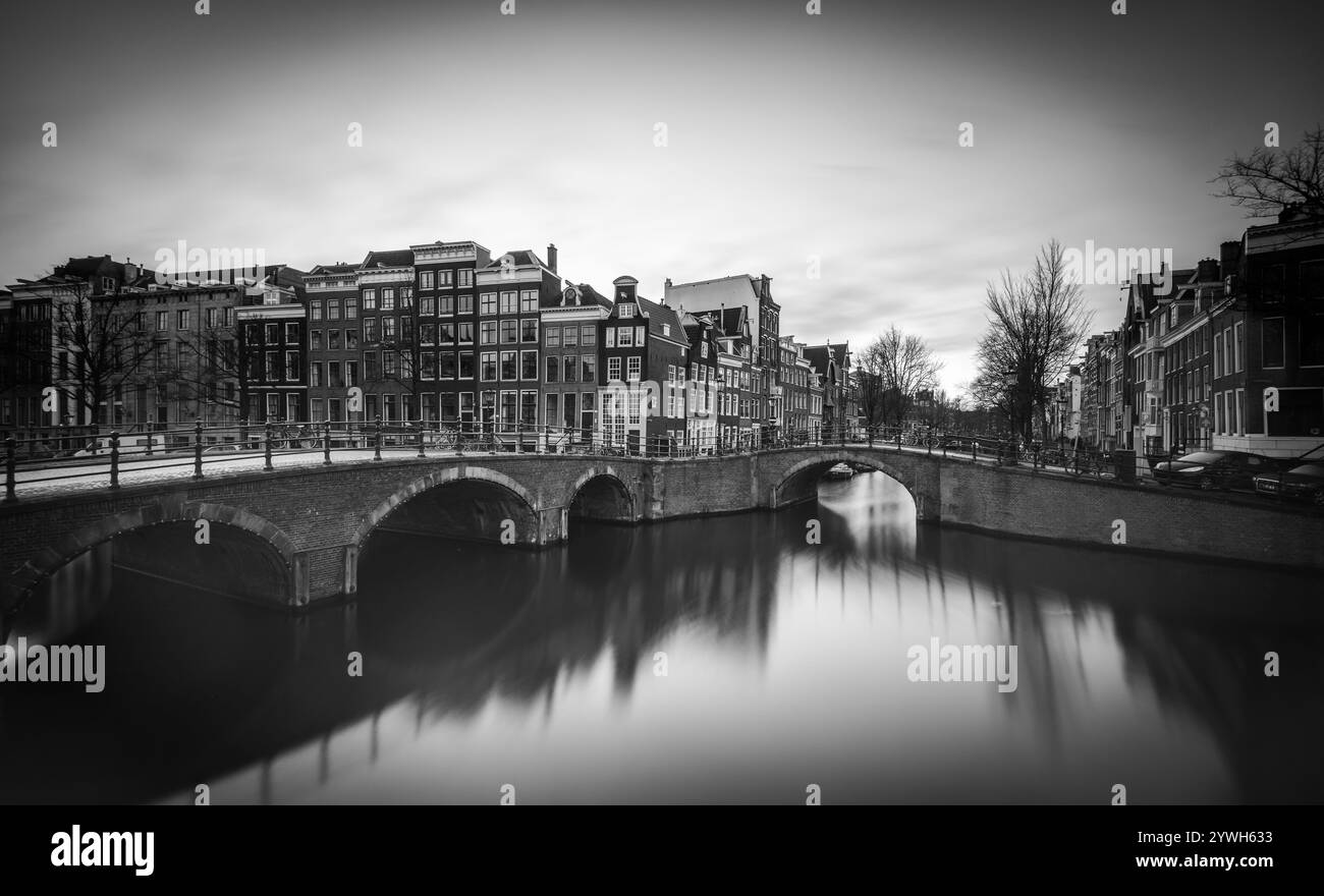 Gli affascinanti canali di Amsterdam riflettono l'architettura storica al crepuscolo Foto Stock