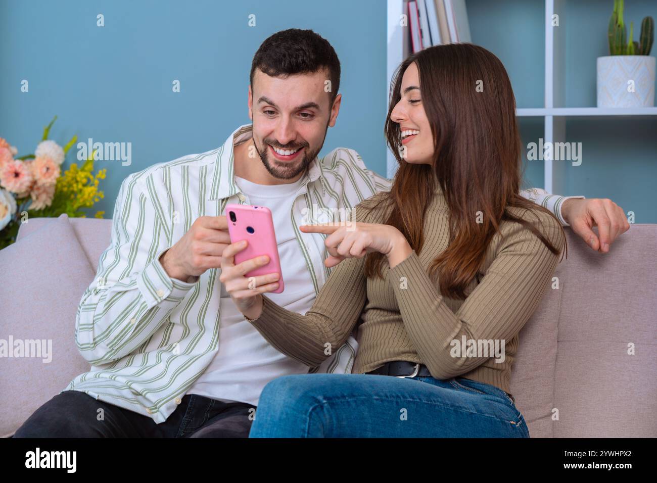 Coppia felice che si diverte un momento guardando uno smartphone rosa. Foto Stock