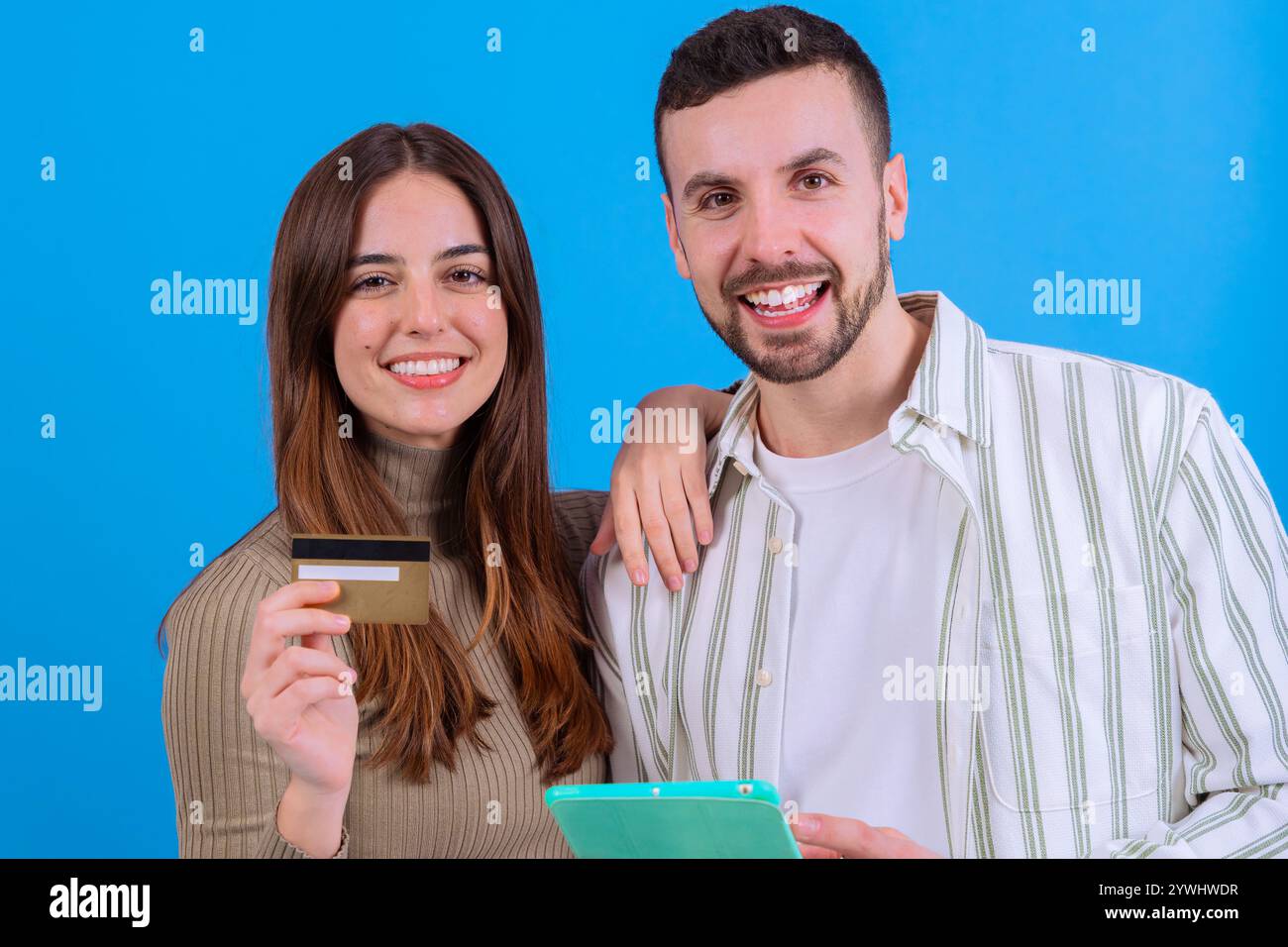 Coppia felice con carta di credito e tablet su sfondo blu. Foto Stock