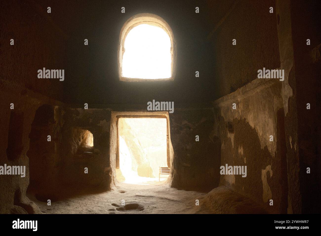 La spettacolare luce del sole entra all'interno del monastero della grotta attraverso la porta del buco, creata dall'erosione naturale della morbida roccia vulcanica Foto Stock