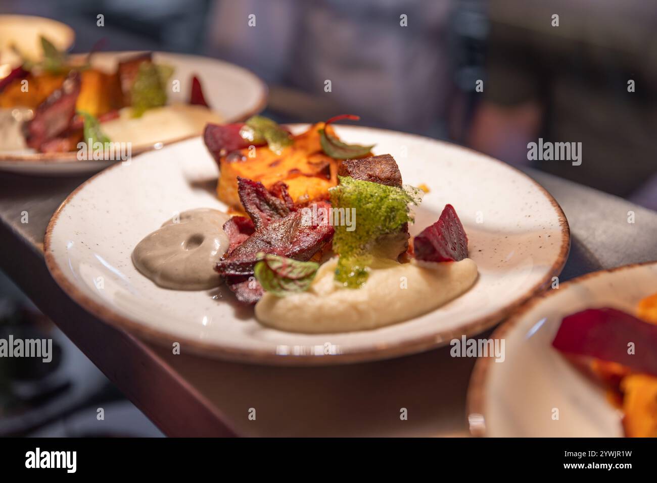 La cucina del ristorante propone eleganti piatti gourmet con polenta, barbabietole arrostite, carne e salsa Foto Stock