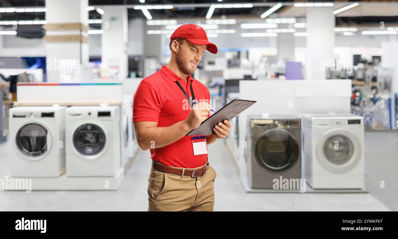 Responsabile del settore retail in un negozio con lavatrici che scrivono un documento Foto Stock