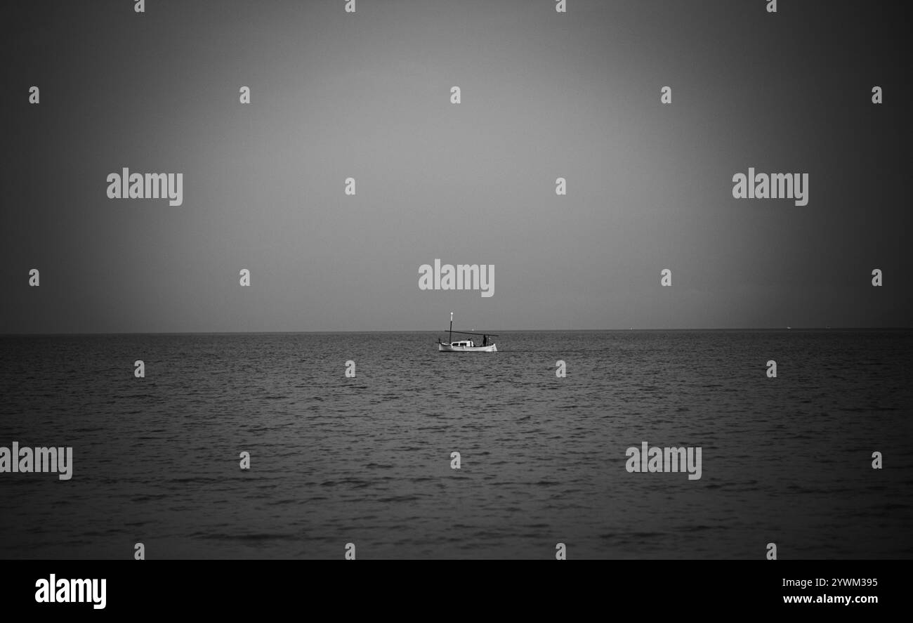 Piccola barca da pesca bianca solitaria nel mare calmo. Foto minimalista a tema marino, adatta per l'uso come carta da parati, sul sito web, per decorazioni interne Foto Stock