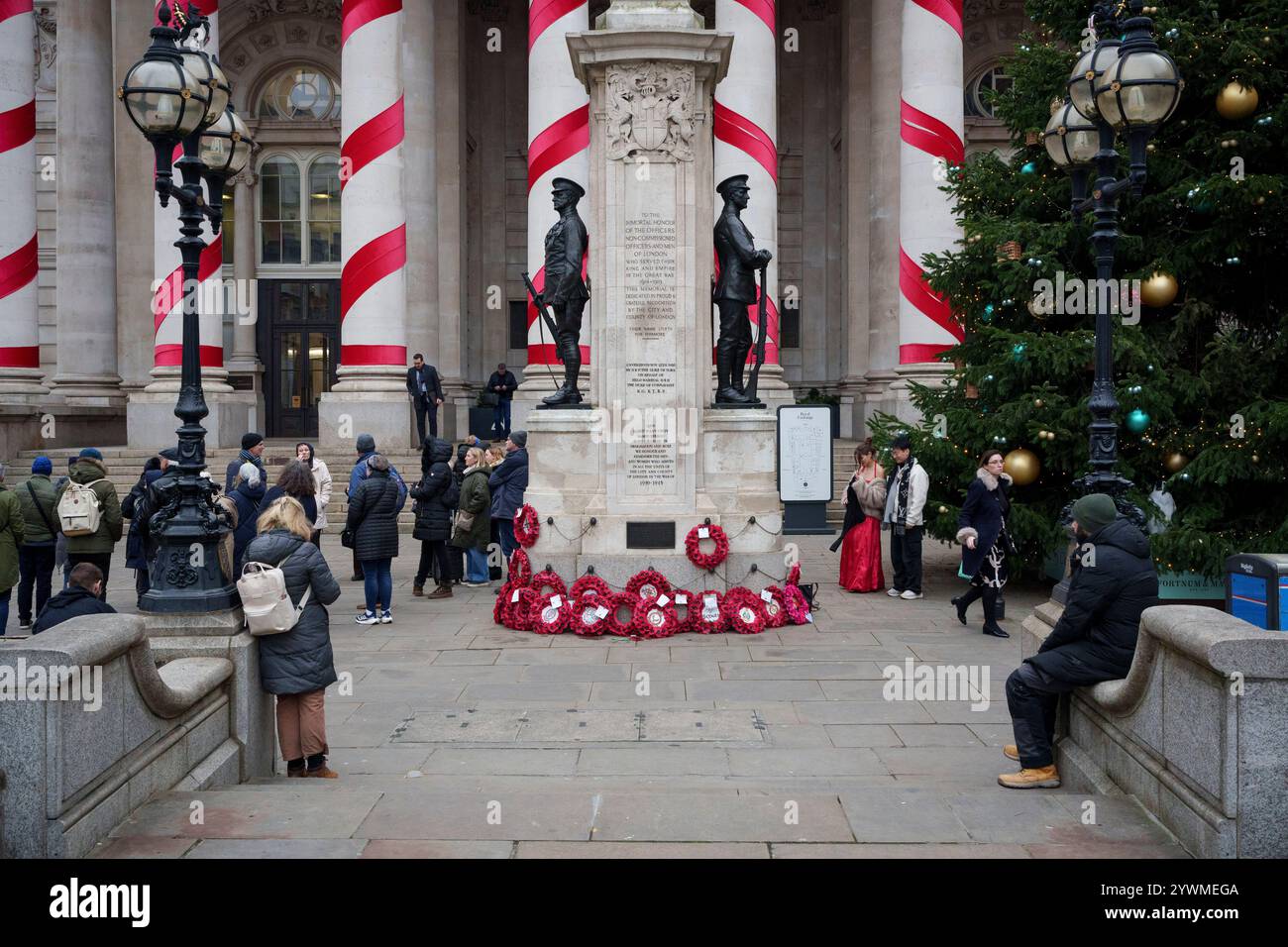 Settimane prima di Natale, operai e visitatori della città e il memoriale di guerra fuori Royal Exchange, presso la Bank nella City di Londra, il quartiere finanziario della capitale, l'11 dicembre 2024, a Londra, Inghilterra. Foto Stock