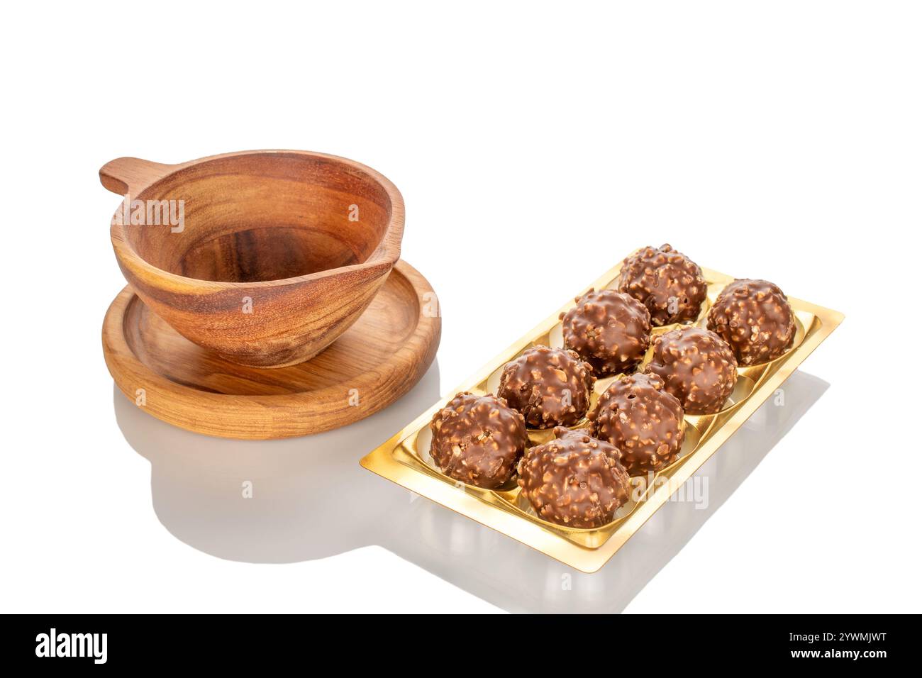 Caramelle al cioccolato con nocciole in una ciotola di legno, primo piano, isolate su sfondo bianco. Foto Stock