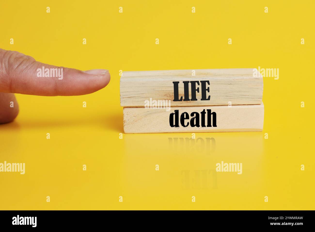 Simbolo di vita o di morte. Concetto parola vita o morte su blocchi di legno. Mano d'affari. Bellissimo sfondo giallo. Concetto di affari e di vita o di morte. Foto Stock