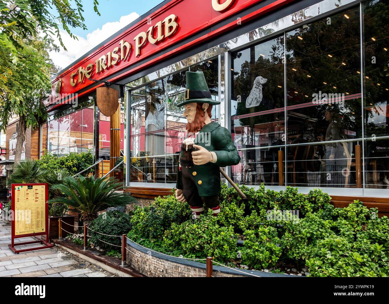 Un variopinto leprechaun saluta i passanti fuori da un vivace pub irlandese a Bodrum, Turkiye. Foto Stock