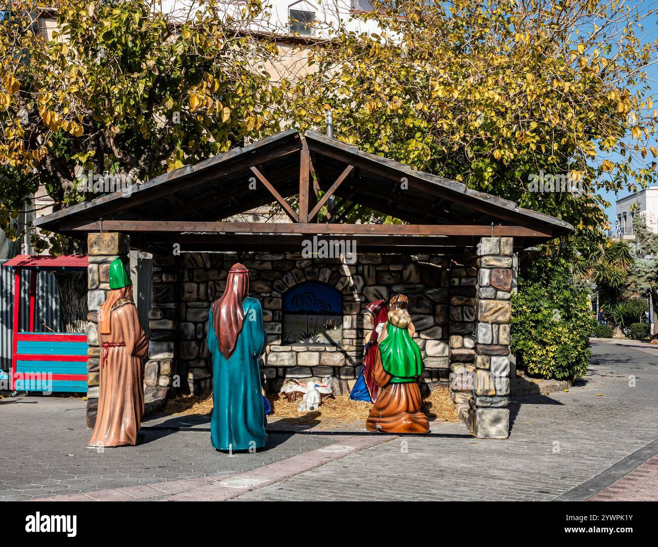 Figure festose a grandezza naturale circondano un presepe rustico, che celebra la nascita di Gesù per le strade di Kos, in Grecia. Foto Stock