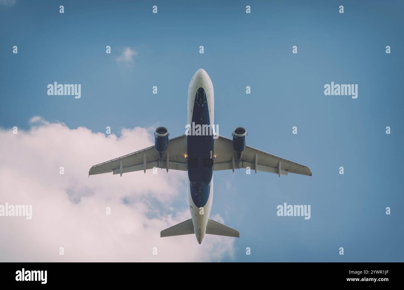 Jet passeggero commerciale che vola in alto contro un cielo blu con nuvole Foto Stock