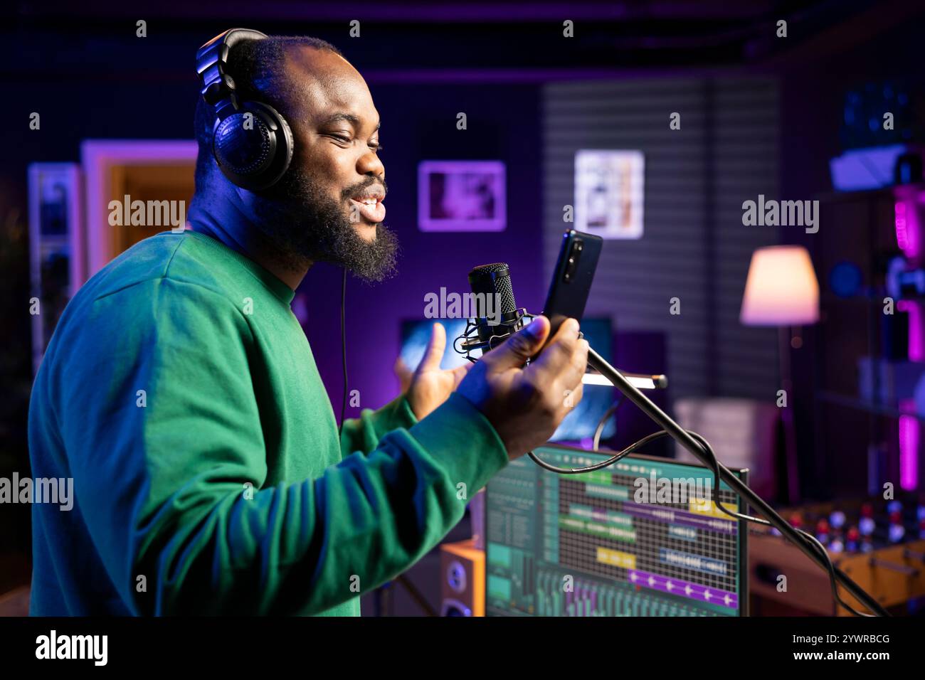 Artista esperto e sicuro di sé che registra la sua nuova canzone prima di una sessione acustica, producendo una colonna sonora nel suo studio di casa con attrezzature stereo. Giovane musicista che esegue una melodia sul microfono. Foto Stock