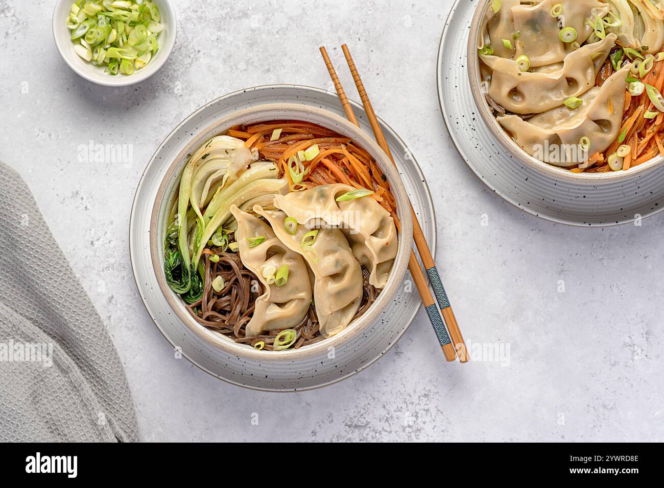 Fotografia gastronomica di zuppa di ramen con gyoza vegetale, soba, spaghetti di grano saraceno, cipolla primaverile, carote, Bok choy, bacchette; cibo vegano, Chines Foto Stock
