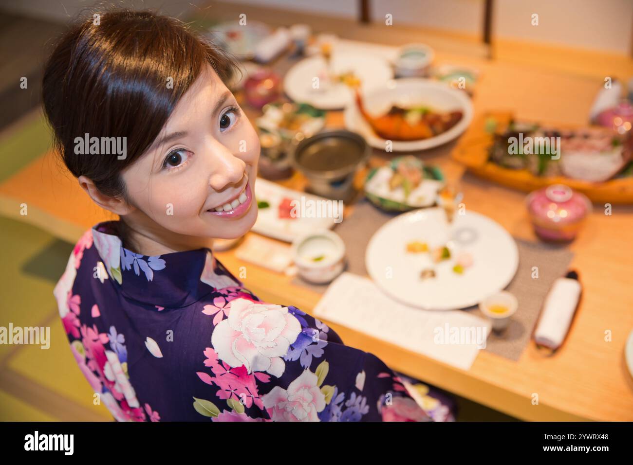 Giovane donna in yukata che si gusta un pasto in un ryokan Foto Stock