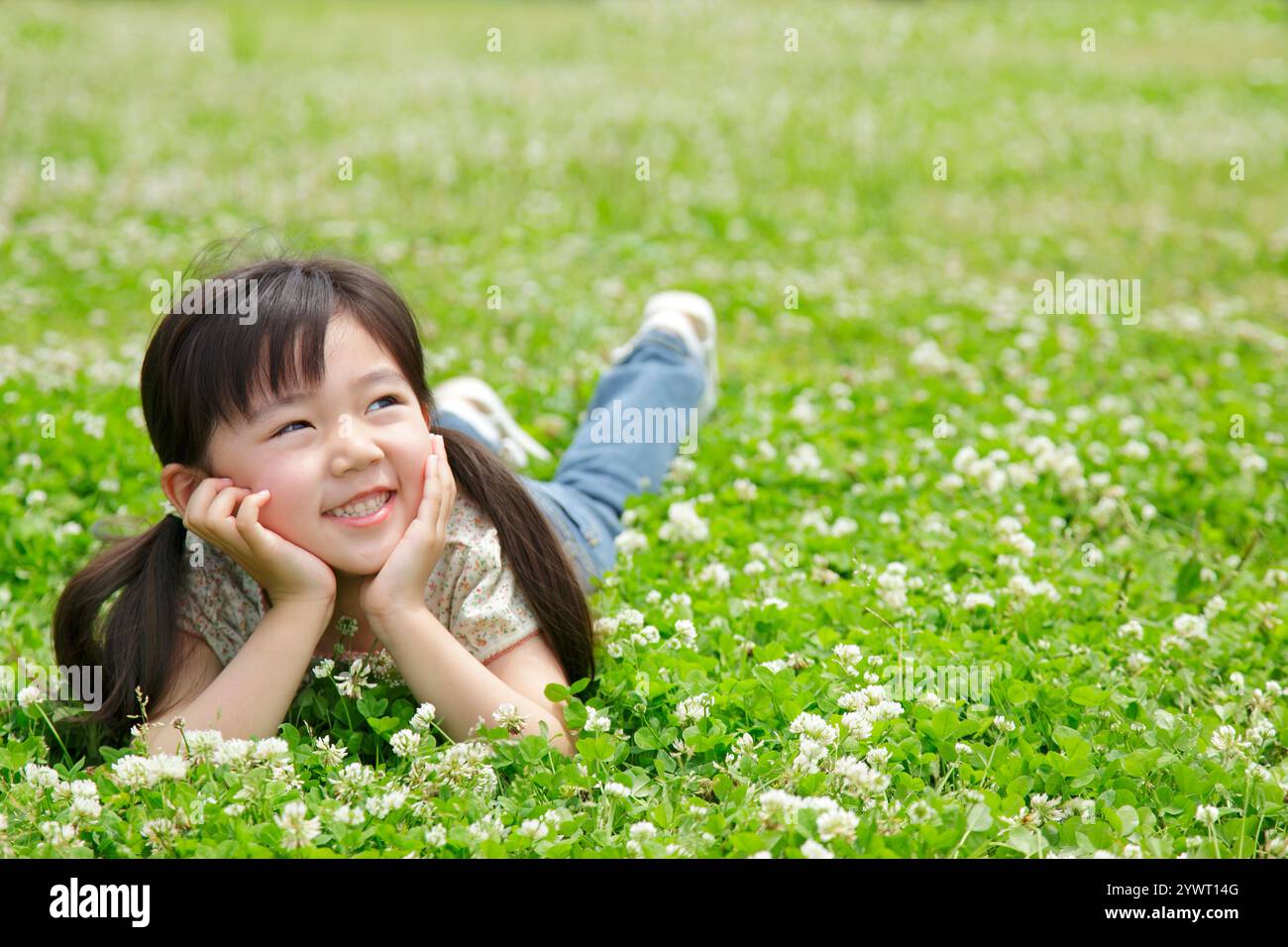 Ragazza che giace sul trifoglio verde Foto Stock