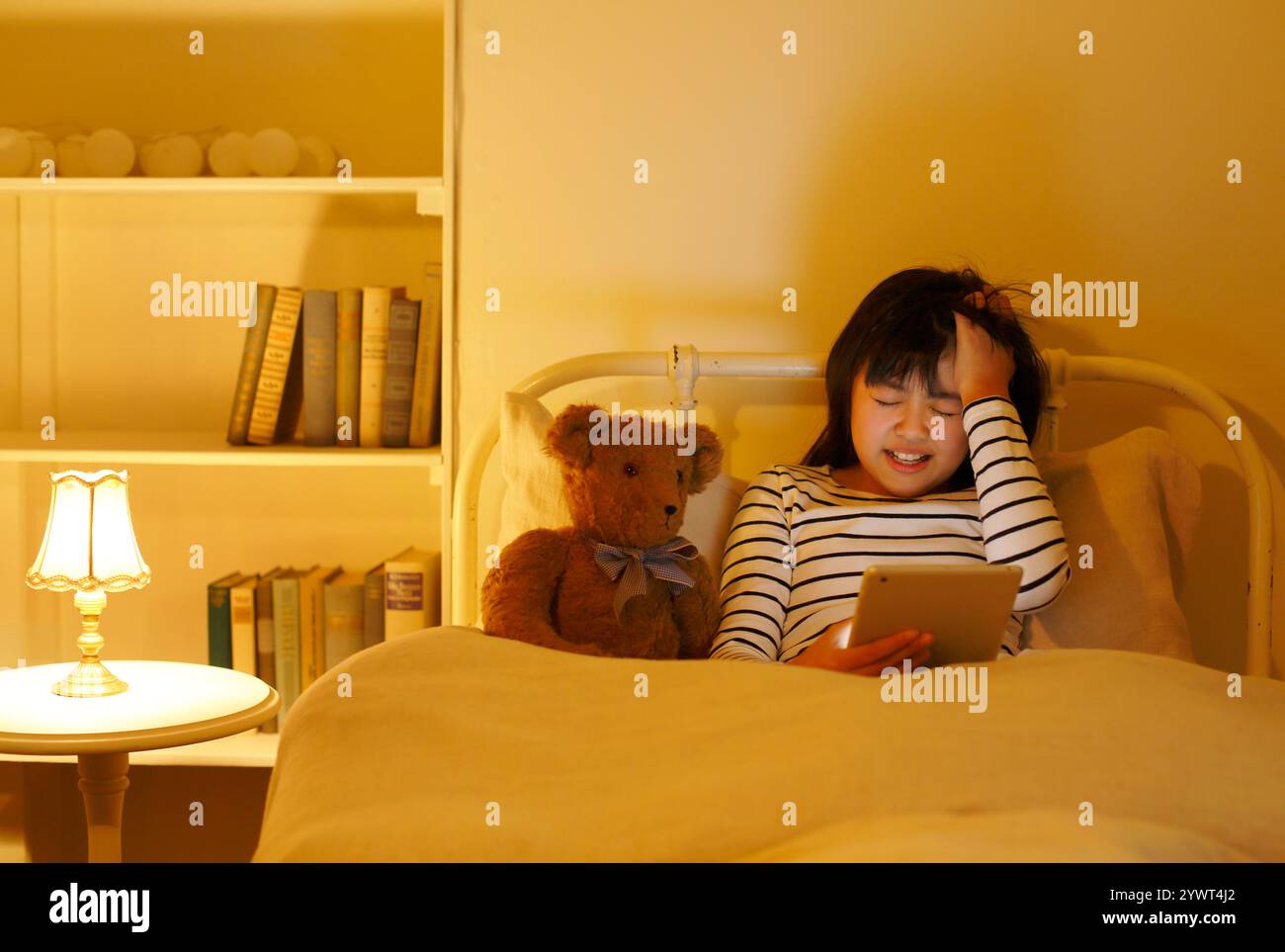 Ragazza che usa il tablet a letto Foto Stock